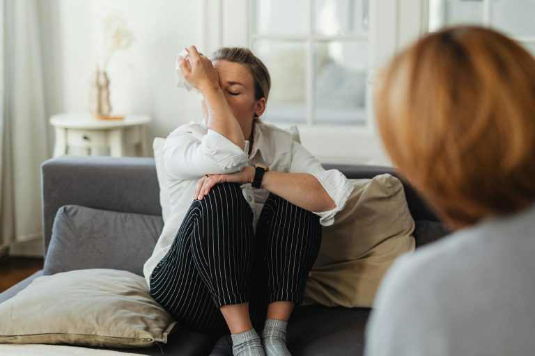 Young woman sitting on a sofa wiping tears: why is my husband watching porn